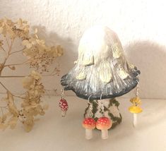 a small mushroom sitting on top of a table next to some plants and mushrooms in front of a white wall