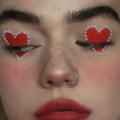 a woman with red and white makeup has hearts painted on her eyes