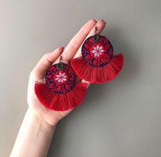 a pair of red tasseled earrings with flowers