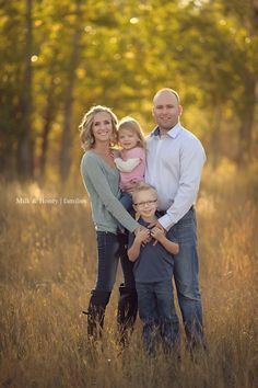 a family posing for a photo in the grass with trees in the backgroud