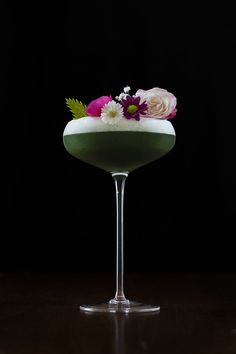 a green cocktail with flowers in it