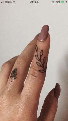 a woman's hand with a small tattoo on her left thumb and the other half of her finger