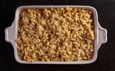 a white dish filled with cereal on top of a black table next to a spoon