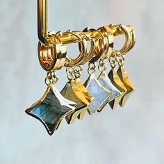 three pairs of earrings hanging from a hook on a wall with gold and silver accents