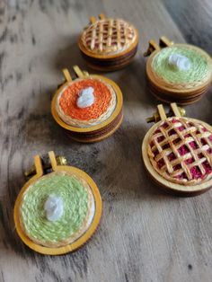 four small wooden baskets with different colored designs on them sitting on a table next to each other