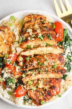 a white plate topped with chicken, rice and veggies next to a fork