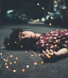 a woman laying on the ground with her eyes closed and lights in the air behind her