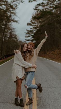 two young women standing on the side of a road with their arms around each other