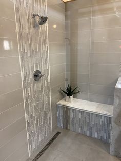 a white tiled bathroom with a plant in the corner