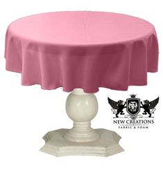 a pink table cloth on top of a white pedestal with a black crest logo in the background