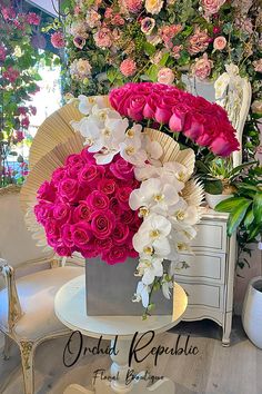 a vase filled with pink and white flowers on top of a table next to a fan