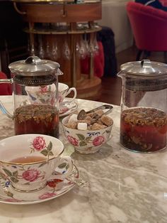 a table topped with cups and saucers filled with food next to a tea pot