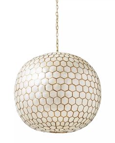 a white ball hanging from a chain on a light fixture with hexagonal pattern