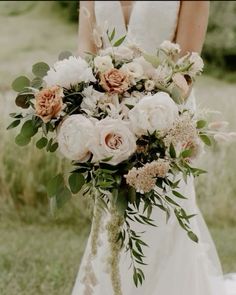 a bridal holding a bouquet of white and peach flowers