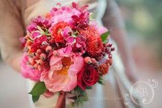 a white bowl filled with colorful flowers on top of a table next to a pillow