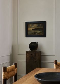 a vase sitting on top of a wooden table next to a black plate and bowl