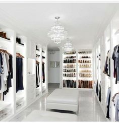 a walk in closet filled with lots of white furniture and shelves full of clothes on hangers