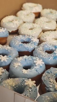 a box filled with blue frosted donuts covered in white sprinkles