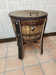 an old wooden barrel table sitting on top of a tile floor next to a wall