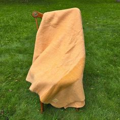 a chair covered in a yellow blanket sitting on top of a green grass covered field