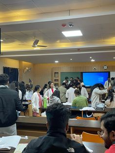 a group of people sitting at desks in front of a screen with the tv on