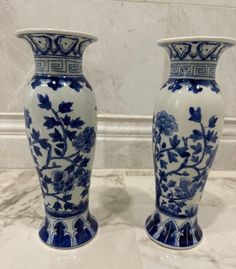 two blue and white vases sitting next to each other on a marble counter top