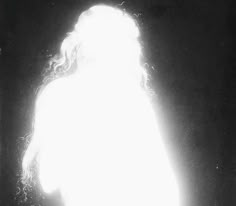 a woman with long hair standing in the dark