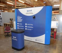 a large blue and white sign in the middle of a room with two trash cans next to it