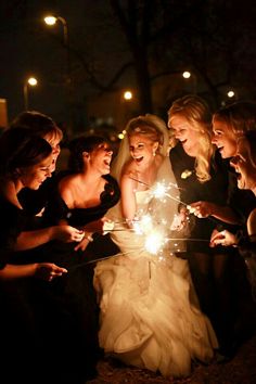 a group of women standing next to each other holding sparklers