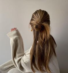 a woman sitting on the floor with her leg up in front of her and wearing a white sweater