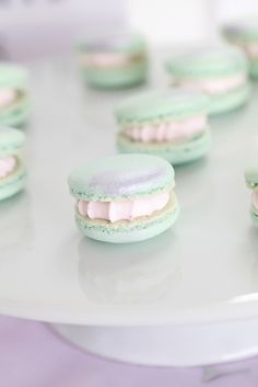 some green and white macaroons with pink frosting on them sitting on a table