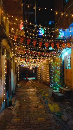 an alley way with lights and decorations on the ceiling, in front of a building