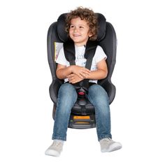 a little boy sitting in a booster seat with his arms crossed and smiling at the camera