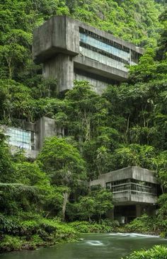 an unusual building in the middle of a jungle with trees on both sides and water running through it