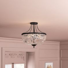 a chandelier hanging from the ceiling in a room with pink walls and white trim