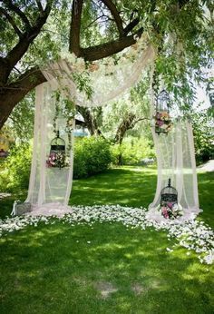 an outdoor ceremony setup with flowers on the ground and white draping over it