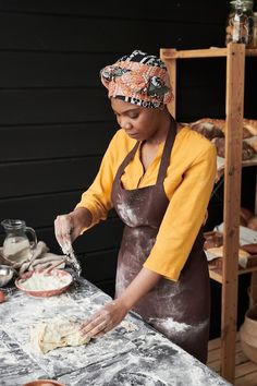 a woman in an apron is kneading dough on a table with utensils