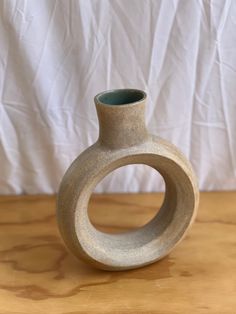 a grey vase sitting on top of a wooden table