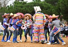 a group of people dressed in colorful costumes and hats standing around each other on a dirt field