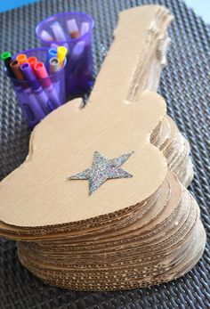 a stack of wooden guitar shaped tags next to colored crayons