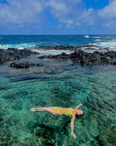 a woman swimming in the ocean with rocks and water