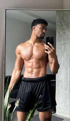 a shirtless man taking a selfie in front of a mirror with his cell phone