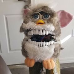 a stuffed animal that is on top of a wooden pole with its mouth wide open