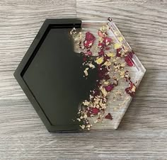 a black tray with flowers on it sitting on a table