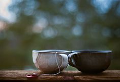 two cups sitting on top of a wooden table next to each other with wires in them