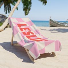 a pink and white checkered beach chair with the word fiesta on it sitting in the sand