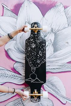 a person is painting a flower on a wall with a skateboard in front of it