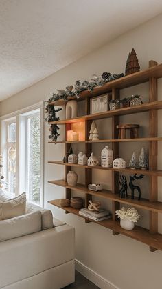 a living room filled with lots of shelves next to a white couch in front of a window