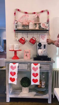 a table with two mugs on it and some decorations hanging from the shelf above