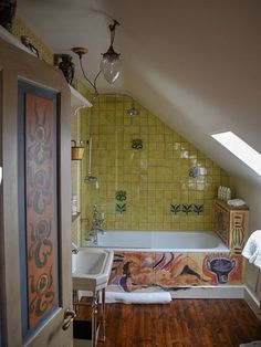 an attic bathroom with yellow tile and wood flooring on the walls, along with a bathtub that has been decorated with colorful tiles